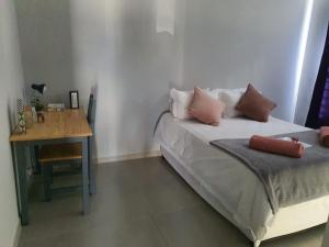 Schlafzimmer mit einem Bett, einem Tisch und einem Schreibtisch in der Unterkunft Stellenbosch Idasvalley Gem in Stellenbosch