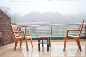 2 stoelen en een tafel op een balkon bij ROYAL HERITAGE in Mahabaleshwar