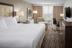 a hotel room with a bed and a desk and chair at Hilton Kansas City Airport in Kansas City