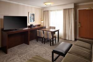 a hotel room with a desk and a television at Embassy Suites Tysons Corner in Tysons Corner