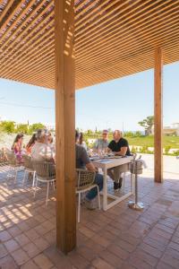 een groep mensen aan een tafel onder een paviljoen bij White Shell Beach Villas in Porches