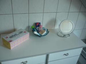 a bathroom counter with a box of cosmetics and a mirror at Ferienwohnung „An der olen Au“ in Tönnhausen