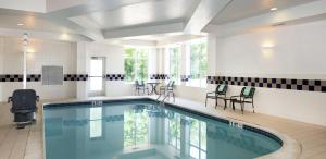 une grande piscine avec des chaises et une table dans l'établissement Hilton Garden Inn Philadelphia-Fort Washington, à Fort Washington