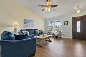a living room with a blue couch and a ceiling fan at The Splash Pad Sleeps 13 w Pool Patio and Garage in Panama City