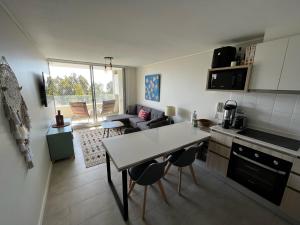 cocina y sala de estar con mesa y sillas en Algarrobo Espectacular piso 10 vista bahía en Algarrobo