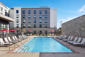uma piscina com espreguiçadeiras e um edifício em Homewood Suites By Hilton Long Beach Airport em Long Beach