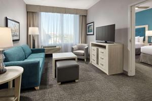 Homewood Suites By Hilton Long Beach Airport في لونغ بيتش: غرفة معيشة مع أريكة زرقاء وتلفزيون