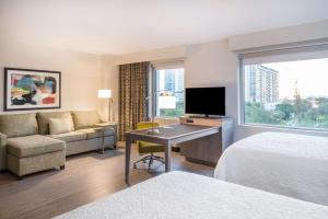 Hampton Inn & Suites Miami Wynwood Design District, FL في ميامي: غرفة فندقية بسرير ومكتب مع تلفزيون