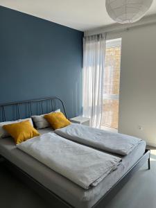 1 dormitorio con paredes azules y 1 cama con almohadas amarillas en Gemütliche Wohnung mit 2 Schlafzimmern auf 75 qm, en Kürnach