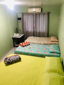 Habitación pequeña con 2 camas y colchón amarillo. en Pousada do Joaquimxdarc, en Natal