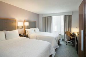 a hotel room with two beds and a desk at Hampton Inn Manhattan Chelsea in New York