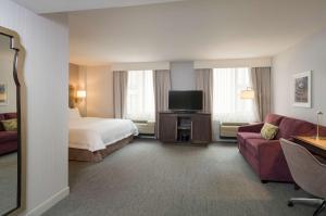 a hotel room with a bed and a couch and a tv at Hampton Inn Manhattan - Times Square South in New York
