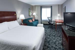 ein Hotelzimmer mit einem Bett und einem TV in der Unterkunft Hilton Garden Inn Naperville/Warrenville in Warrenville