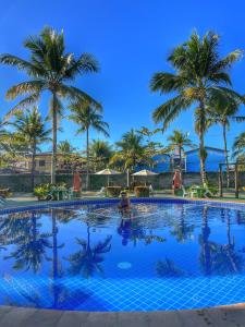 a large swimming pool with palm trees in the background at Condomínio Golden Dolphin Village in Porto Seguro