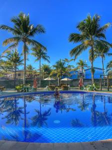 una gran piscina con palmeras en el fondo en Condomínio Golden Dolphin Village, en Porto Seguro