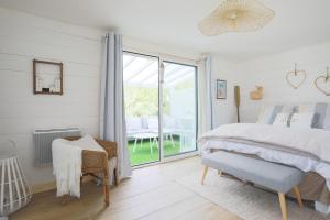 a white bedroom with a bed and a window at lodge avec vue sur la rivière in Lannion