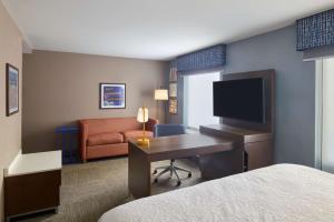 ein Hotelzimmer mit einem Bett und einem Schreibtisch mit einem TV in der Unterkunft Hampton Inn & Suites Providence / Smithfield in Smithfield