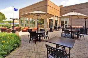 an outdoor patio with tables and chairs and umbrellas at Hilton Garden Inn Lake Forest Mettawa in Lake Forest