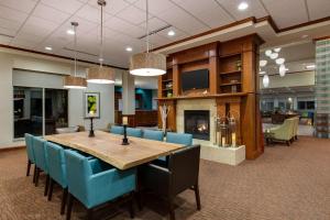 a dining room with a table and chairs and a fireplace at Hilton Garden Inn Lake Forest Mettawa in Lake Forest