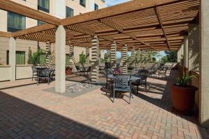 Hampton Inn & Suites Waco-South في واكو: فناء به طاولات وكراسي تحت بروغولا خشبي