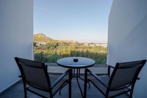 two chairs and a table in front of a window at Mousikorama Apartments in Faliraki