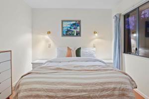 a white bedroom with a large bed and a window at Taupo Beachfront Escape 12min to Town - Free Wifi in Waitahanui