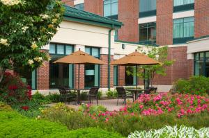 a courtyard with tables and umbrellas in front of a building at Hilton Garden Inn Hartford South/Glastonbury in Glastonbury