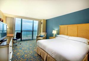 a hotel room with a bed and a balcony at Hilton Daytona Beach Resort in Daytona Beach