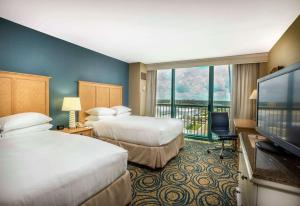 a hotel room with two beds and a flat screen tv at Hilton Daytona Beach Resort in Daytona Beach