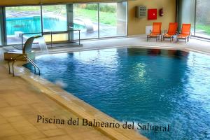 uma piscina com cadeiras laranja num edifício em CASA RURAL ARBEQUINA, Primavera en el Valle del Ambroz em Casas del Monte