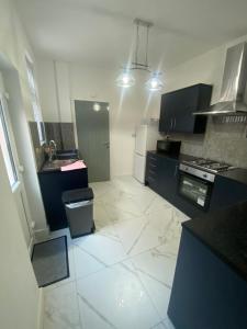 een keuken met zwarte kasten en een witte tegelvloer bij Luxury Fully Furnished Bedroom in Leicester