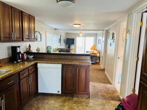 a kitchen with wooden cabinets and a white dishwasher at Hidden Treasure in Holden Beach