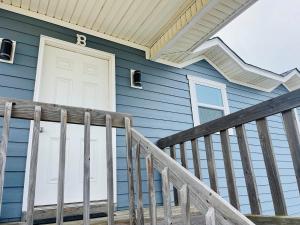 a blue house with a white door and a porch at Serenitee in Holden Beach