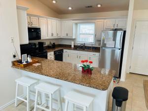 a kitchen with white cabinets and a counter with stools at Serenitee in Holden Beach