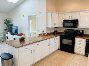 a kitchen with white cabinets and a black appliance at Serenitee in Holden Beach