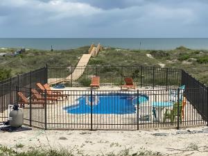a cage with a playground with a pool and chairs at Somewhere South home in Holden Beach