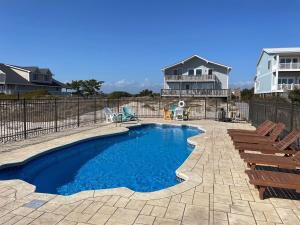 a swimming pool with chairs and a house at Somewhere South home in Holden Beach