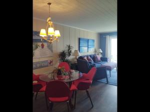 uma sala de estar com uma mesa e cadeiras vermelhas em Next 2 Paradise-203 em Holden Beach