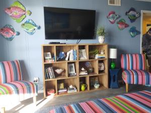 a living room with a tv and a book shelf at Next 2 Paradise-203 in Holden Beach
