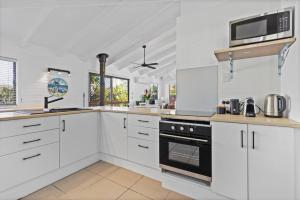 a kitchen with white cabinets and a stove top oven at Pet friendly family escape in Coolum Beach