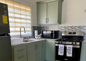 a kitchen with green cabinets and a stove and a sink at Peaceful Fully Equipped 3BR Villa in Arima