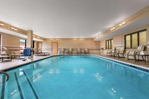 ein großer Pool in einem Hotel mit Stühlen und Tischen in der Unterkunft Hampton Inn Binghamton/Johnson City in Binghamton