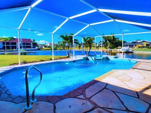 a large swimming pool with a blue umbrella over it at On The Water! Sleeps 12! 2 King Masters, Golf, Fishing, Bbq, Pool, Spa, Pvt Yard in Cape Coral