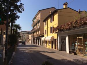 a street with a yellow building and a car driving down a street at Welcome Traveller Borgo Cavour Apartaments in Bardolino