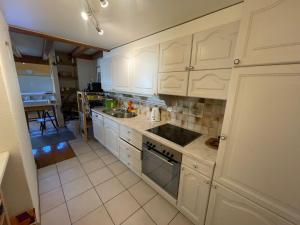 a kitchen with white cabinets and a stove top oven at Chambre atypique in Saint-Blaise