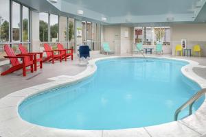einen großen Pool mit roten und blauen Stühlen und Tischen in der Unterkunft Home2 Suites By Hilton Longmont in Longmont