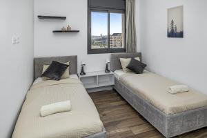 two beds in a room with a window at Jerusalem Luxury Apartments by IB Properties in Jerusalem