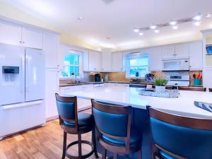 a kitchen with white cabinets and a large island with bar stools at On The Water! Sleeps 12! 2 King Masters, Golf, Fishing, Bbq, Pool, Spa, Pvt Yard in Cape Coral