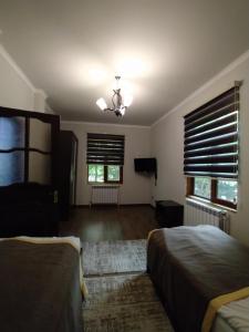 a bedroom with two beds and a television and windows at Qusar Qala Hotel in Qusar