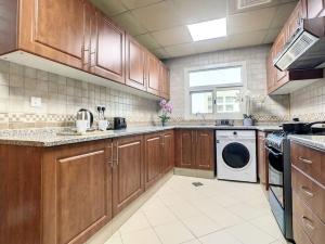 a kitchen with wooden cabinets and a washer and dryer at Key View - Silicon Star in Dubai